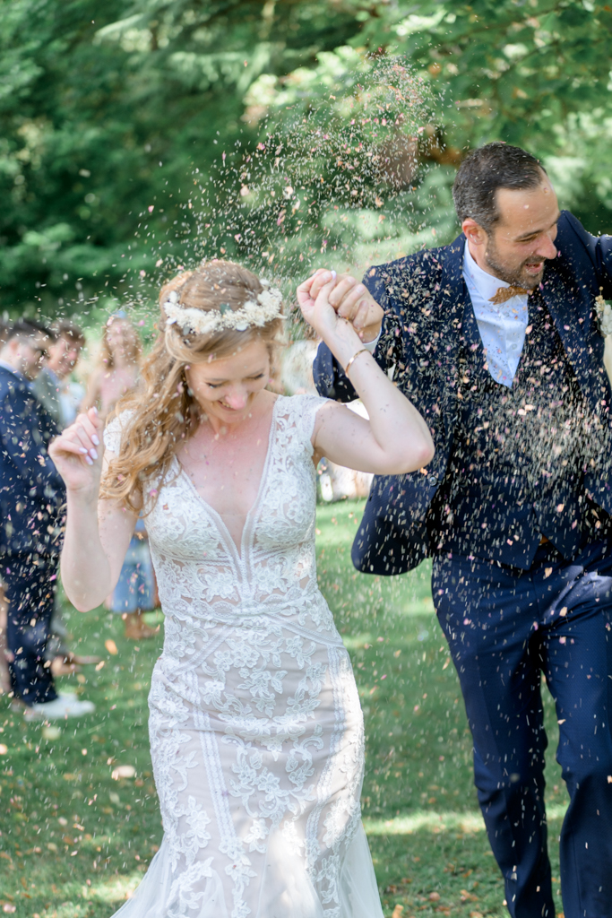 Photographie du mariage d'un couple de mariés noyé dans un jet de pétales de fleur au Moulin XII. Photographe Patrick PIERRE