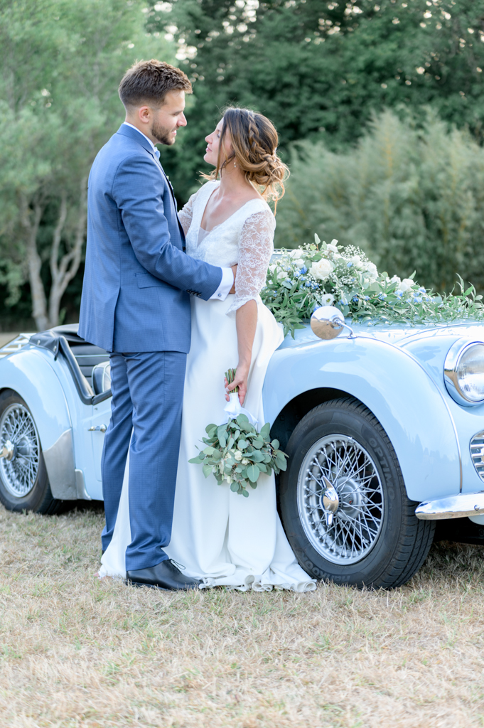 Photographie du mariage d'un couple de mariés au domaine de Montireau. Ils sont adossés à une voiture de collection. Photographe Patrick PIERRE