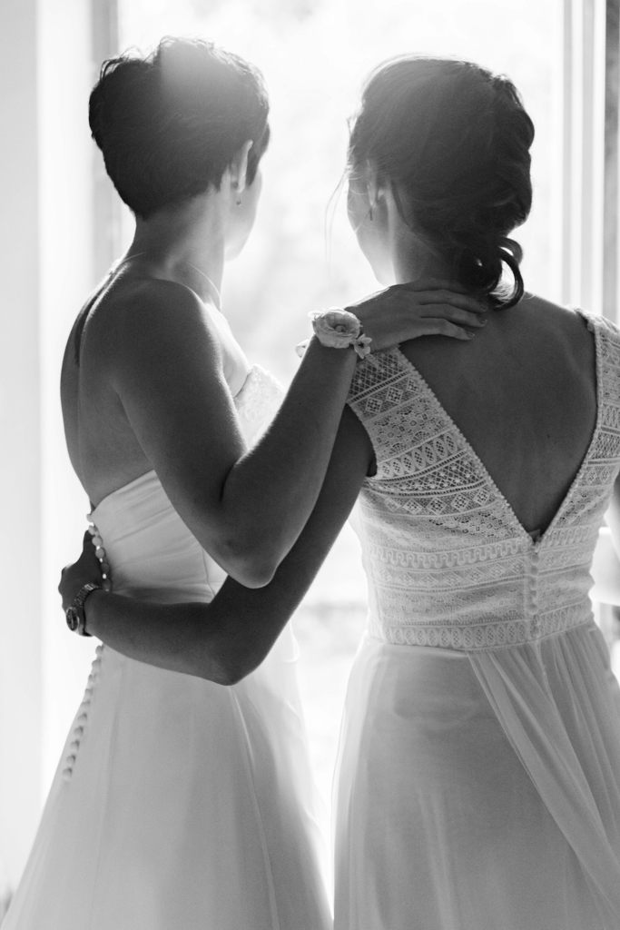 Photographie du mariage de deux jeunes femmes regardant la lumière provenant d'une porte ouverte. Cette lumière symbolise l'amour et la nouvelle vie qui les attend. Photographe Patrick PIERRE